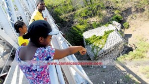 Residents looking on from the Rio Minho bridge, in May Pen, Clarendon, from which Oraine Stephenson jumped to his death Wednesday.